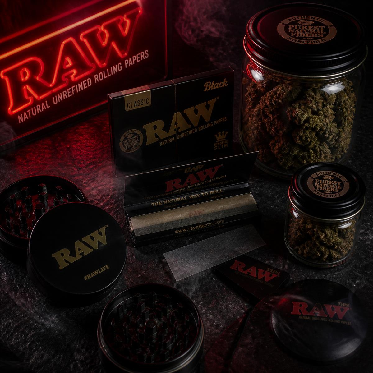 Rolling papers, grinders and jars of hemp flower on a dark counter